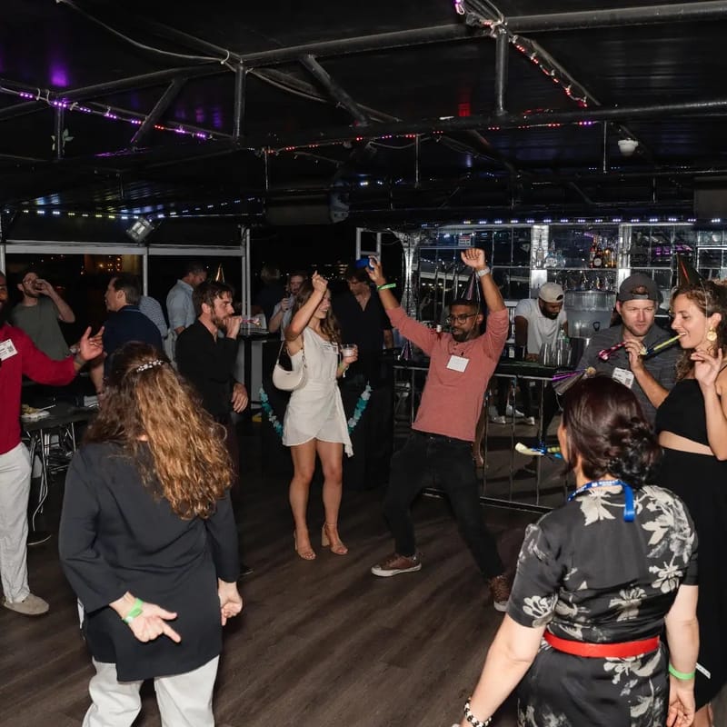 Guests dancing on the lower deck of the Ben Franklin Yacht under purple party lights