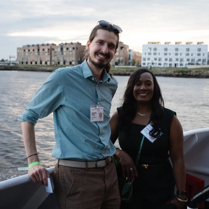 Chris Gittings and a guest leaning on the railing of the yacht at sunset