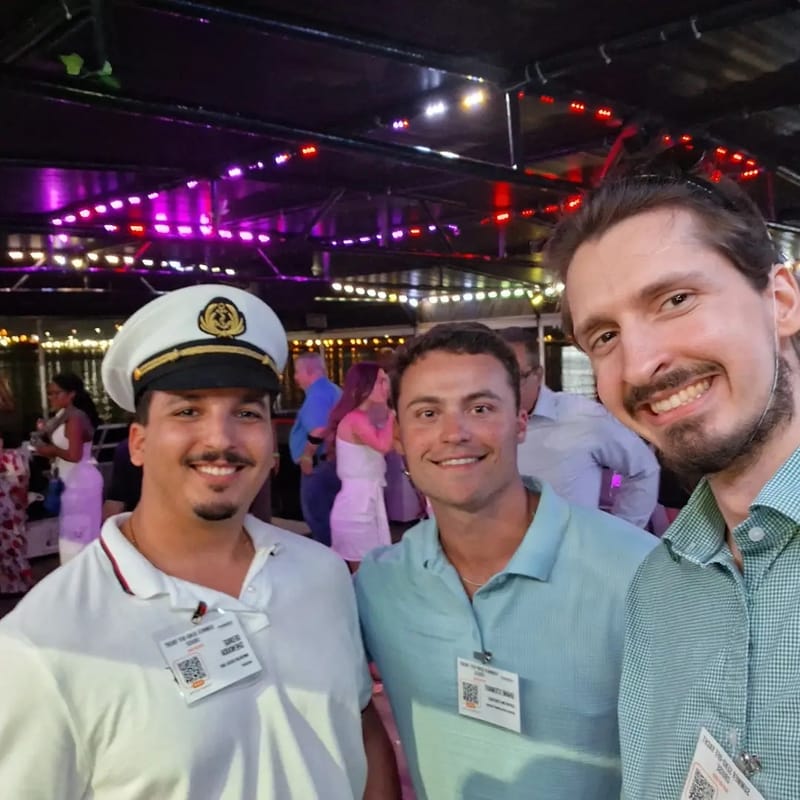 Chris Gittings, a guest in a captain's hat and another guest taking a selfie under the yacht's party lights