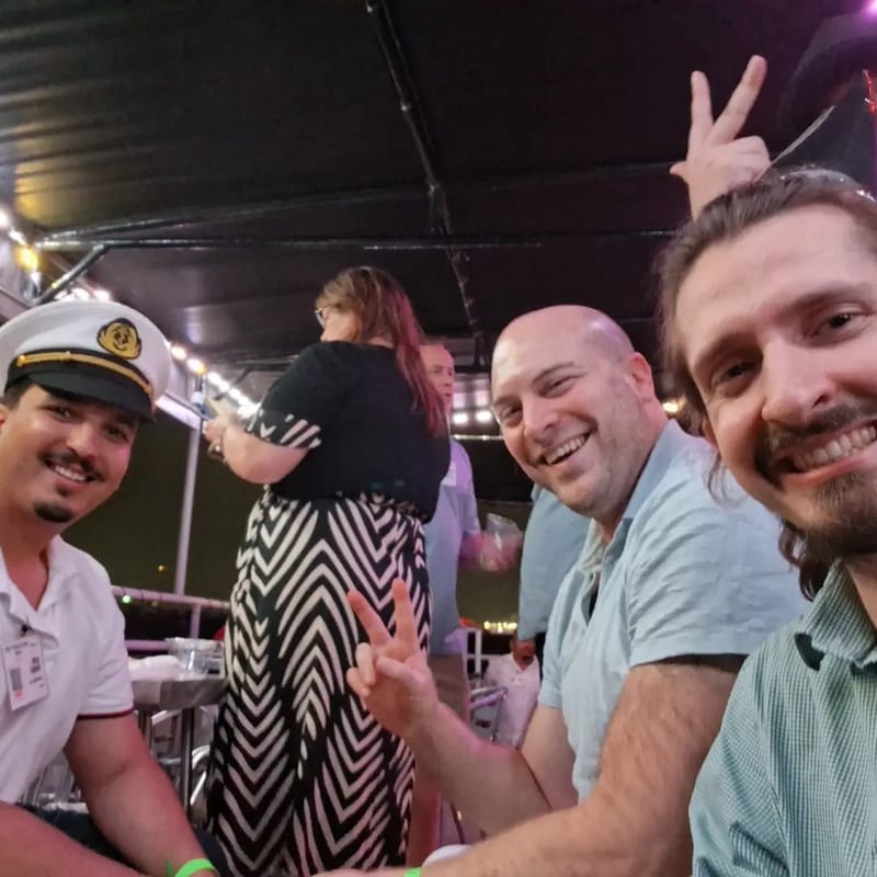 Chris Gittings taking a selfie with guests on the yacht's deck, one giving a peace sign