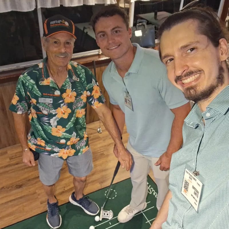 Chris Gittings taking a selfie with two guests beside a putting green on the yacht